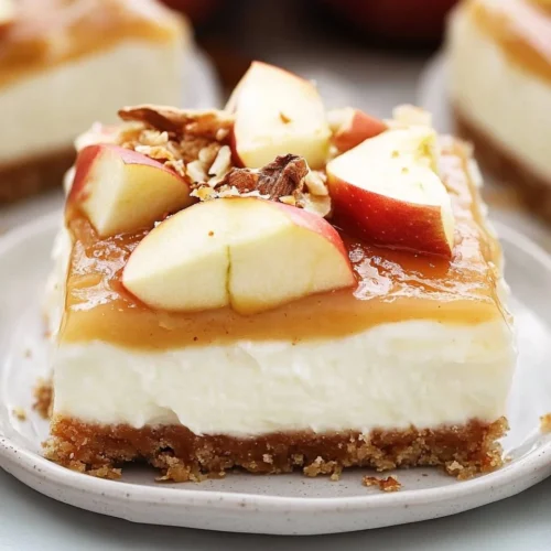 A close-up of a no‑bake layered dessert bar featuring a buttery graham‑cracker crust topped with creamy cream-cheese layer, tender apple pie filling, fluffy whipped topping, caramel drizzle, and chopped pecans.